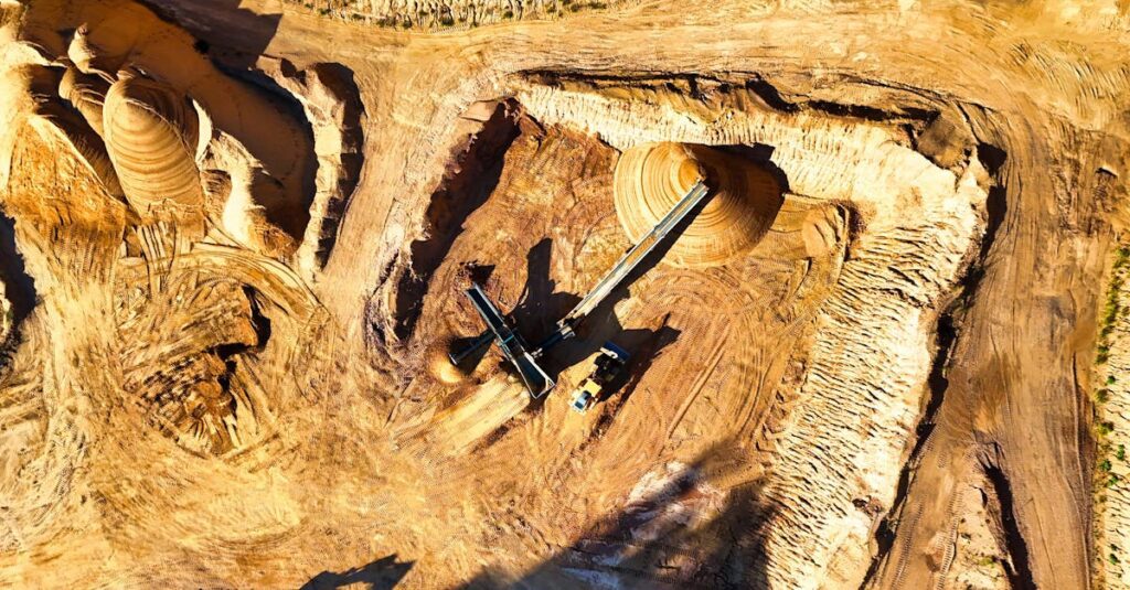 Aerial shot of a vast open-pit mine with visible heavy machinery excavating minerals.